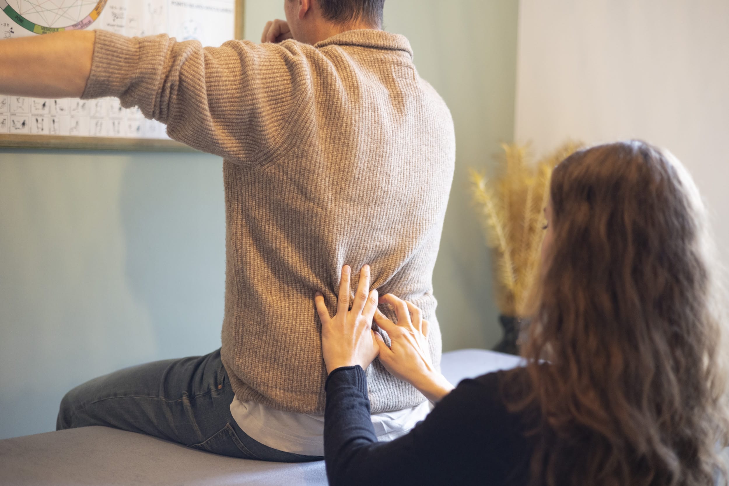 Camille qui travaille sur des points du dos de son consultant qui est assis sur la table