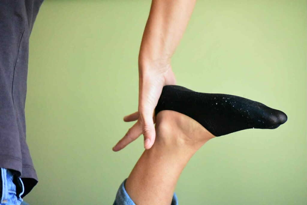 Zoom sur la main de Camille travaillant sur le pied de sa consultante en chaussette