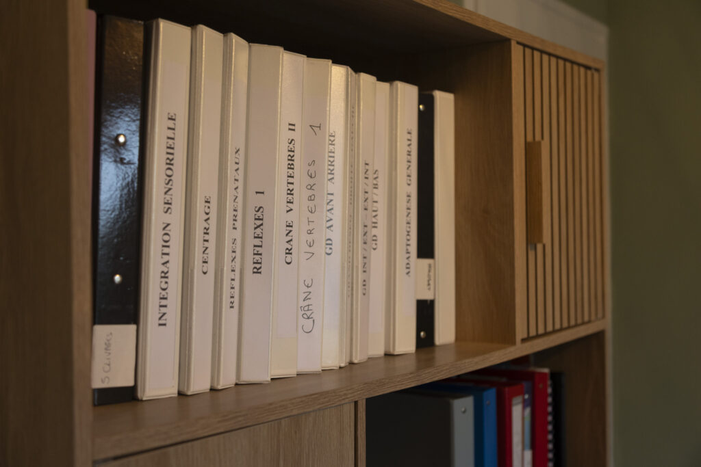classeurs de travail de kinésiologie de Camille dans l'étagère du cabinet